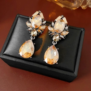 Macro shot of vintage teardrop earrings with champagne crystals on black leather base