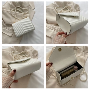 Detail of white V-quilted crossbody bag with pearl strap and gold chain accent