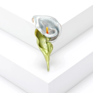Exquisite silver calla lily brooch with green enamel leaves on a white geometric stand