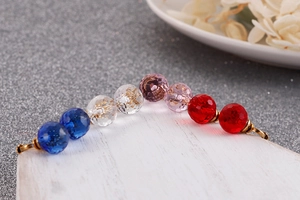 Macro view of colorful faceted crystal beads and gold hooks on white wood surface