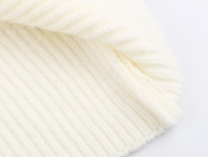 Makroaufnahme der weichen Rippstrick-Textur und Kunstpelzbesatz am weißen Kleid