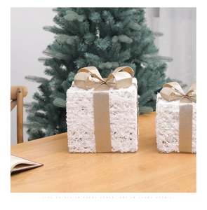 Set of two white Christmas gift boxes with gold ribbons on a cozy wooden table scene