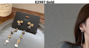 Close-up of asymmetrical long tassel earrings with golden bow and zircon details