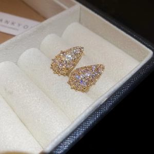 Macro shot of gold teardrop stud earrings with pave-set cubic zirconia in a jewelry box