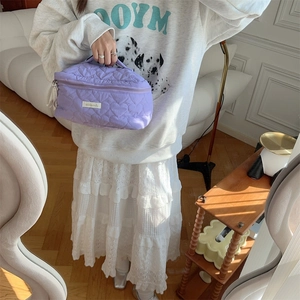 Vista dettagliata della borsa da trucco viola con trapuntatura a cuore tenuta da una modella