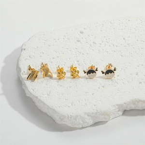 Golden earring set featuring lightning bolt, leaf with gems, and cartoon girl portrait designs