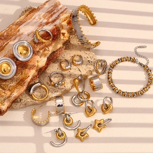 Detail view of two-tone gold and silver jewelry set on textured stone with aesthetic shadows
