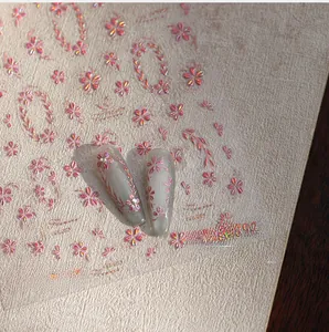 Macro detail of 3D embossed pink metallic flower nail stickers on manicure tips