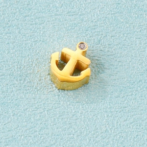 Polished gold anchor pendant with a sparkling crystal stone on light blue background