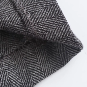 Close-up of grey herringbone fabric texture and stitching on wide leg trousers