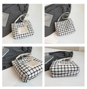 Detail view of black and white checkered tweed tote bag with cat charm and front pocket