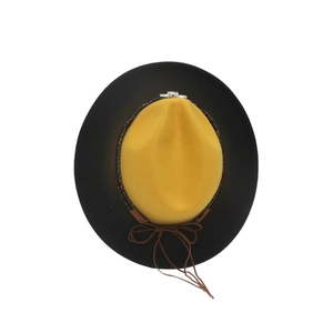 Detail view of yellow felt fedora with black brim and skull ornament on the rainbow band