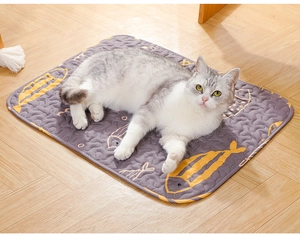 Detail of grey quilted pet mat with yellow fish patterns and a cat resting on it