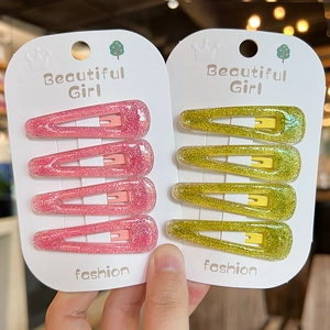 Close-up of glittery pink and yellow-green teardrop hair clips set on card packaging