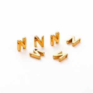 Close-up of six gold plated letter beads with 1.8mm holes for DIY jewelry making