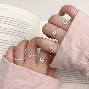 S925 sterling silver rings with charms and twisted bands shown held against a book