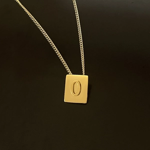 Macro view of 18K gold plated stainless steel square pendant featuring letter O engraving