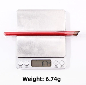 Macro shot of a red angled eyebrow brush on a digital scale weighing exactly 6.74 grams