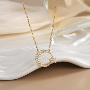 Detailed close-up of a gold-plated moon and star pendant necklace with white zircons