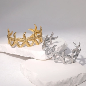 Bracciali a stella marina in oro e argento su sfondo minimalista in pietra bianca