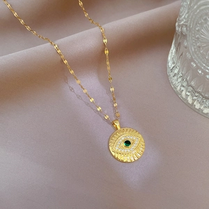 Detailed close-up of gold eye necklace featuring a green gemstone and micro-pave zircons