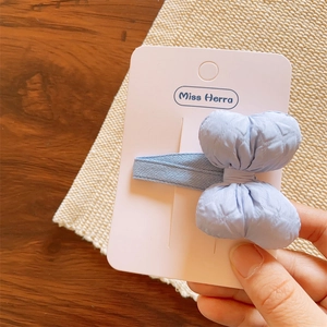 Close-up of a light blue quilted fabric bow hair clip on a display card for girls