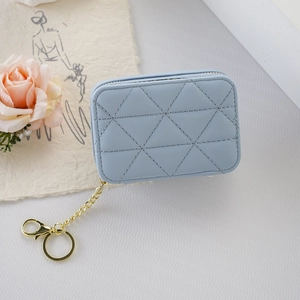 Portable blue quilted mini lipstick pouch with gold chain and mirror on white desktop