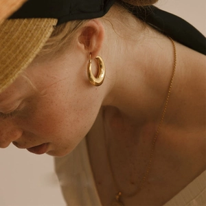 Polished minimalist gold-plated oval hoop earrings worn by model for an elegant vintage look