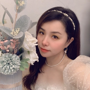 Elegante set di gioielli con perle e cerchietto floreale dorato su una modella asiatica