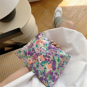Close-up of a floral cotton makeup bag held against a white dress in a cozy setting
