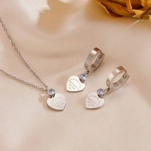 Elegant stainless steel heart necklace and earring set with small zircons on beige cloth