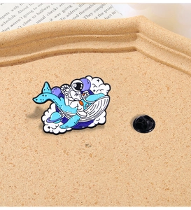 Detailed close-up of a cartoon astronaut riding a whale enamel pin on a cork background