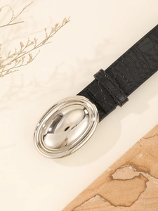 Detail of black crocodile texture belt with a large oval silver buckle on a rock