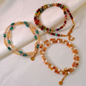 Détail de colliers en perles de pierres naturelles et breloques en acier doré 18 carats