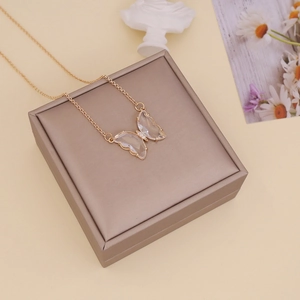 Macro detail of a golden butterfly pendant with clear glass wings on a jewelry box