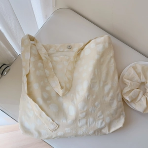 Detail of cream polka dot textured cotton tote bag with matching scrunchie and magnetic buckle