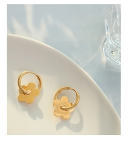 Detail of 18K gold plated flower hoop earrings on a minimalist white ceramic plate