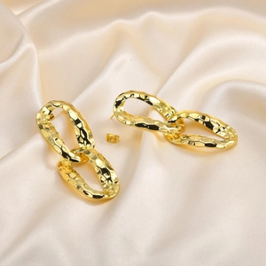 Golden hammer-textured double oval earrings on elegant beige silk background