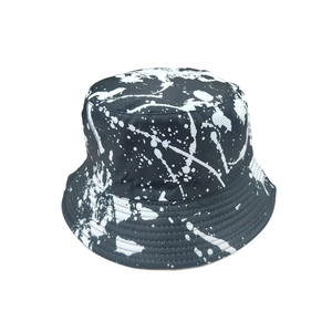 Detail of white paint splash pattern and reinforced stitching on a black bucket hat