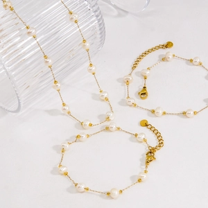 Three-piece set of minimalist gold titanium jewelry with pearls featuring a necklace and bracelets
