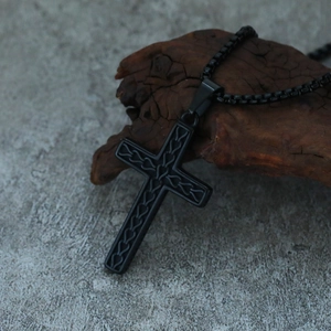 Detailed macro view of black metal cross pendant with heart pattern on rustic wood