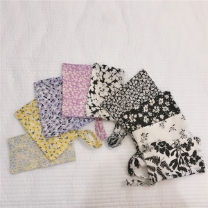 Vue à plat de plusieurs pochettes en coton à fleurs avec cordons de différentes couleurs