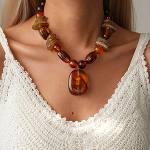 Vintage amber resin beaded necklace with large oval pendant on white crochet vest
