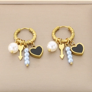 Detail of gold heart earrings with dangling black heart and pearl charms on leather