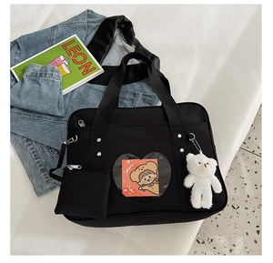 Detail of black JK style Ita bag featuring a heart window and plush bear pendant detail