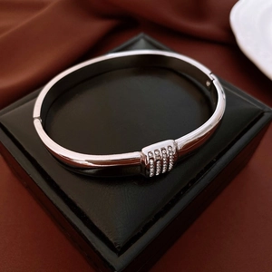 Detailed macro of silver hinged bangle with rows of clear micro-pave crystals on black case