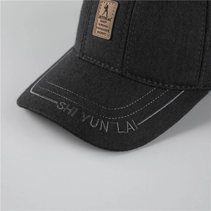 Detailed close-up of dark grey twill baseball cap with leather patch and embroidery