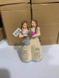 Detail of female resin figurines featuring silver tops, beige skirts and pink flower balls