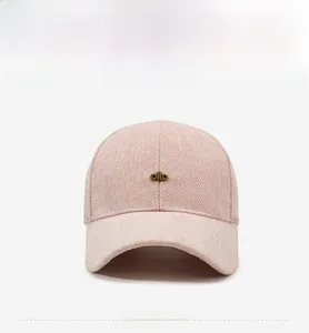 Close-up of pink herringbone fabric and gold logo on the baseball cap front