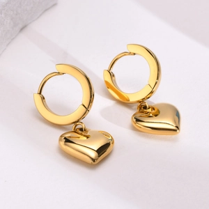 Macro shot of polished gold heart earrings featuring sleek clicker hoops on white background